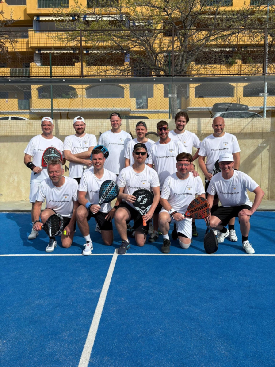 Padeltogether-grupp i vita matchtröjor på padelbana i Marbella